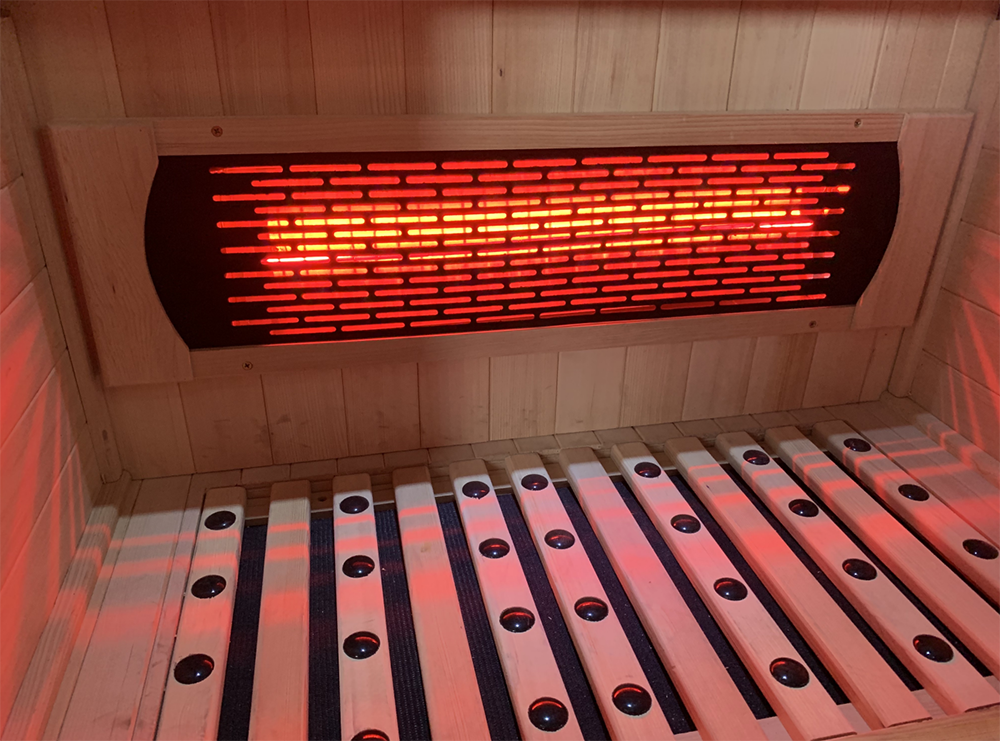 Close view of a lit infrared heater above the slatted floor grille inside the Lumin Three cabin